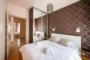 - une chambre avec un grand lit blanc et un miroir dans l'établissement Obrzeżna Beige Apartment, à Varsovie