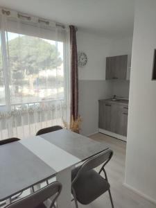 une cuisine avec une table et des chaises et une fenêtre dans l'établissement studio avec piscine, à Gruissan