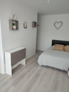 une chambre blanche avec un lit et un bureau dans l'établissement studio avec piscine, à Gruissan