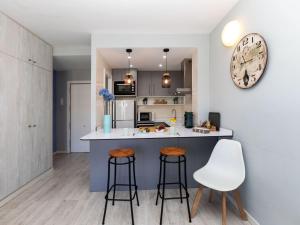 una cucina con due sgabelli da bar e un orologio sul muro di Apartment Lotus by Interhome a Blanes