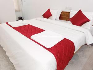 dwa łóżka z czerwono-białymi kocami i poduszkami w obiekcie Skylight Residency Yercaud w mieście Yercaud