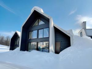 una casa negra en la nieve en Niseko White Villas1, en Niseko