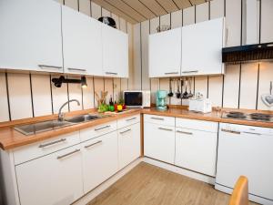 una cocina con armarios blancos y fregadero en Apartment Backbord by Interhome, en Norddeich