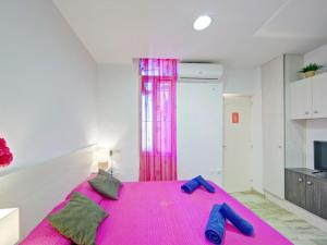 1 dormitorio con 1 cama rosa y 2 zapatillas azules en Studio Muralla Roja-3 by Interhome, en Calpe
