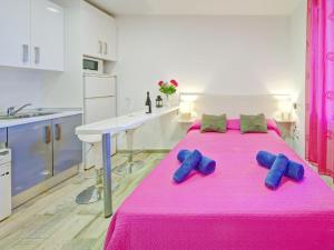 Una gran cama rosa en una cocina con dos zapatos azules. en Studio Muralla Roja-3 by Interhome, en Calpe