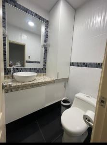 La salle de bains blanche est pourvue d'un lavabo et de toilettes. dans l'établissement Departamento amplio para familias, à Guayaquil