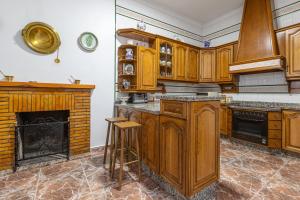 cocina con armarios de madera y chimenea en Casa Margarita, en Cañete la Real