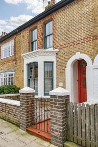 a brick house with a red door and a fence at Ravenscourt - Stylish home by the sea in Whitstable