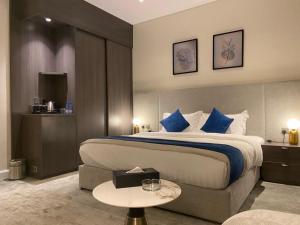 una camera d'albergo con un grande letto con cuscini blu di فندق سافوي جدة Savoye Hotel a Gedda
