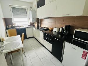 a kitchen with white cabinets and a table and a microwave at Brasov 3C DELUX 2 in Braşov