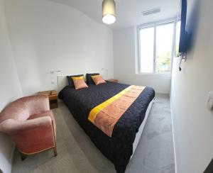 ein Schlafzimmer mit einem Bett, einem Stuhl und einem Fenster in der Unterkunft Vacances en Famille ou entre Amis in Saint-Raphaël