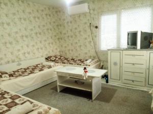 a bedroom with two beds and a tv and a table at Guest House Emiliya in Ovchartsi