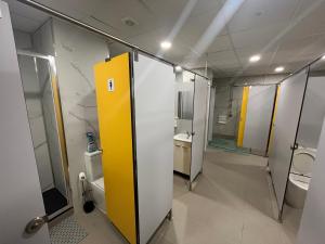 baño con puerta amarilla, lavabos y aseos en Hostel del Templo de Debod en Madrid