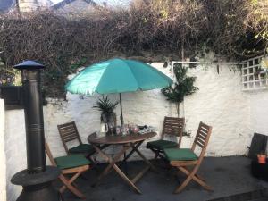 a table and chairs with a blue umbrella at Downtown Cottage Conwy in Conwy