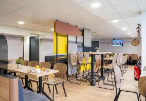 a restaurant with tables and chairs and a tv at B&B HOTEL Paris Porte de Châtillon in Châtillon