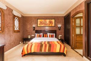 マラケシュにあるRiad Ushuaia La Villa - Centre Marrakechのベッドルーム1室(ベッド1台、テーブル2台、絵画付)