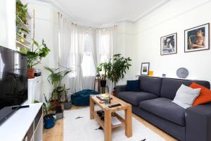 a living room with a blue couch and a table at Charming Victorian 1BR Retreat in the Heart of London in London