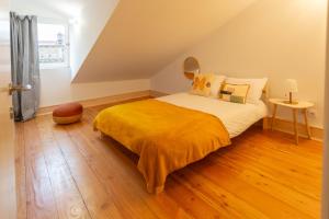 a bedroom with a bed with a yellow blanket at Vinum Apartamentos 1890 in Coimbra
