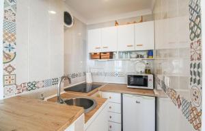 a small kitchen with white cabinets and a sink at Beach Front Apartment In Algarrobo-costa With Outdoor Swimming Pool in Algarrobo-Costa