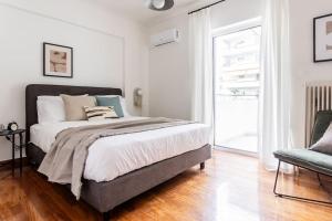 - une chambre avec un grand lit et une chaise dans l'établissement Faliro Sunlit 3BR Apartment by UPSTREET, à Athènes