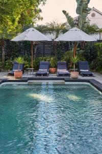 a swimming pool with two chairs and umbrellas at The Robertson Small Hotel and Spa by The Living Journey Collection in Robertson