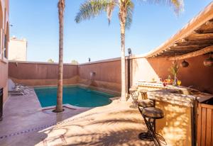 a backyard with a swimming pool and palm trees at Riad Ushuaia avec piscine - Centre Marrakech in Marrakesh