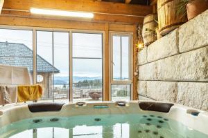 bañera en una habitación con ventana grande en Ameisberger - Landhaus, en Mollmannsreith