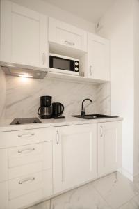 uma cozinha branca com um lavatório e um micro-ondas em Onyx by Baltic Home em Międzyzdroje