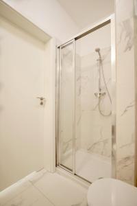 uma casa de banho branca com um chuveiro e um WC. em Onyx by Baltic Home em Międzyzdroje
