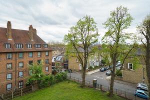Blick auf eine Stadtstraße mit Gebäuden und Bäumen in der Unterkunft Lovely Apartment in Victoria Park Village in London