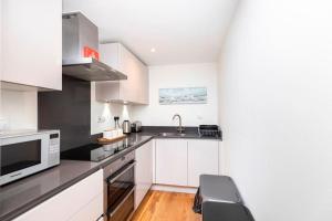 uma cozinha com armários brancos, um lavatório e um micro-ondas em Bournecoast: spacious and modern near beach-FM8501 em Bournemouth