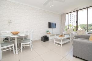 a white living room with a table and a couch at 423 Breakers Resort in Durban