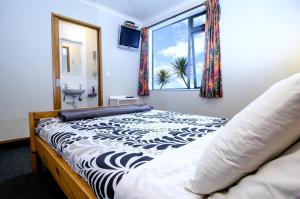 a bed in a bedroom with a white bedspread at Rainbow Lodge Backpackers in Taupo