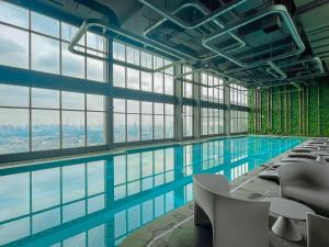 - une piscine avec des chaises dans un bâtiment doté de fenêtres dans l'établissement Rosee House - Luxury apartment in Vinhomes Smart City, à Nam Tu Liem