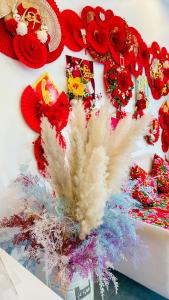 a table with a vase filled with red flowers and feathers at Sele House in Hà Tiên