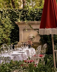 Hôtel Particulier Montmartre في باريس: طاولة مع كؤوس للنبيذ ومظلة حمراء