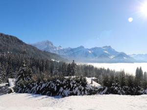 a snow covered mountain range with trees and the sun at Apartment La-Ina by Interhome in Chesières