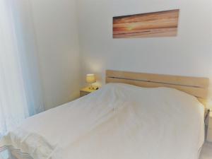 - un lit blanc dans une chambre avec une photo sur le mur dans l'établissement Apartment Landhaus St- Georg-3 by Interhome, à Bad Gastein