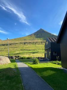 a house in a field with a mountain in the background at Okkara summarhús við Gjógv - Luxury cottage - Unique location in Við Gjógv