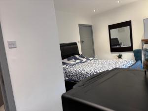 a bedroom with a bed and a computer monitor at Romford Cosy Studio Flat in Havering atte Bower