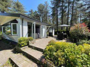 een klein wit huis met een patio en een aantal struiken bij Luxe vakantiehuis in het bos in Overbroek