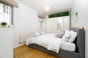 um quarto branco com uma cama grande e uma janela em Lovely Apartment in Victoria Park Village em Londres