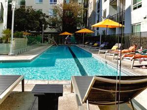 a swimming pool with people laying on chairs and umbrellas at Creative 2 Levels Penthouse in Los Angeles