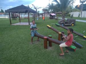 two children playing in a park with play equipment at Cabo frio Condomínio dos pássaros in Cabo Frio