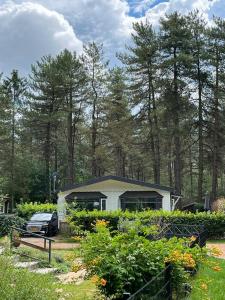 een huis met een auto ervoor geparkeerd bij Luxe vakantiehuis in het bos in Overbroek