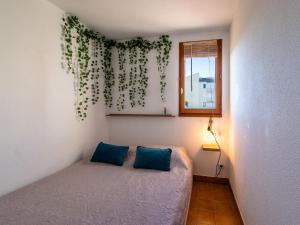 um quarto com uma cama com almofadas azuis e uma janela em Apartment Les Maisons sur la Plage-12 by Interhome em Narbonne Plage