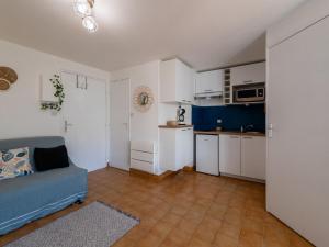 uma sala de estar com um sofá azul e uma cozinha em Apartment Les Maisons sur la Plage-12 by Interhome em Narbonne Plage