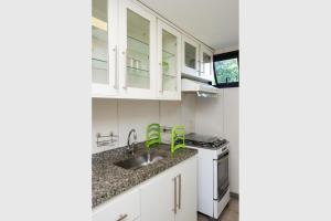 a kitchen with white cabinets and a sink at Apartamento Boa Viagem Niterói Rio de Janeiro in Niterói