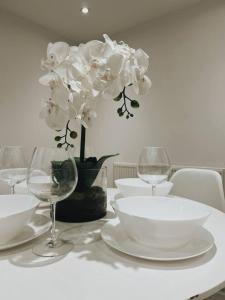 una mesa con platos y vasos blancos y una flor en Stunning 3-Bed House in Oldbury en Birmingham