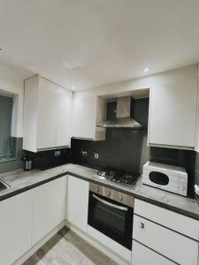 a kitchen with white cabinets and a stove top oven at Stunning 3-Bed House in Oldbury in Birmingham